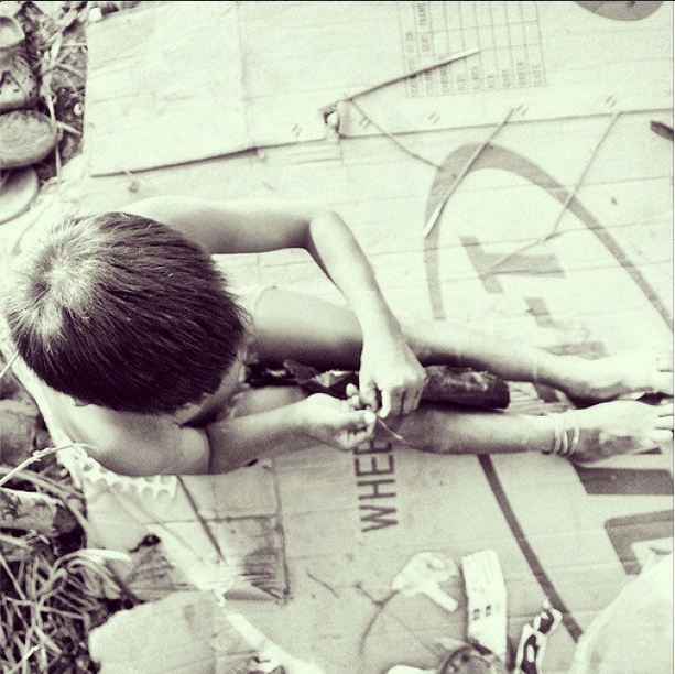 Un niño intenta arman un pagapayo con palos, una bolsa negra de basura y un mecate