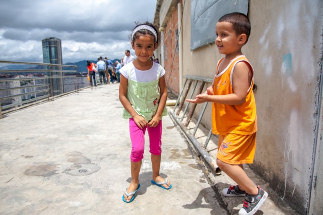 Niños juegan en la terraza del piso 27 de la Torre de David, protegidos por una endeble baranda